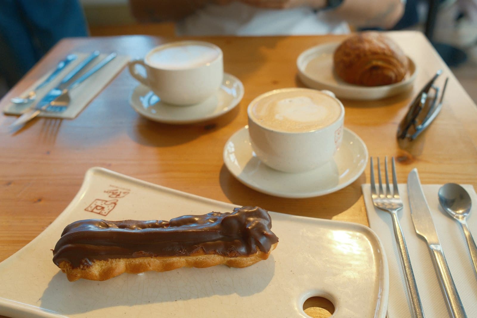 Two coffees and pastries laid out on a wooden brunch table