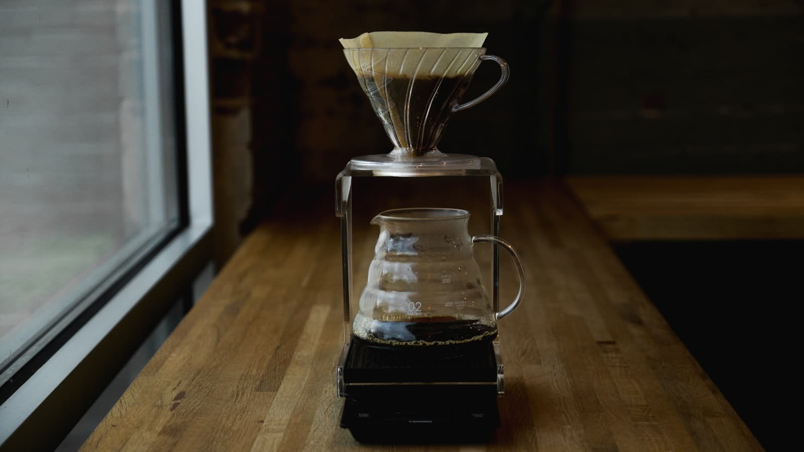 A coffee carafe and brewing kit on a table near a window