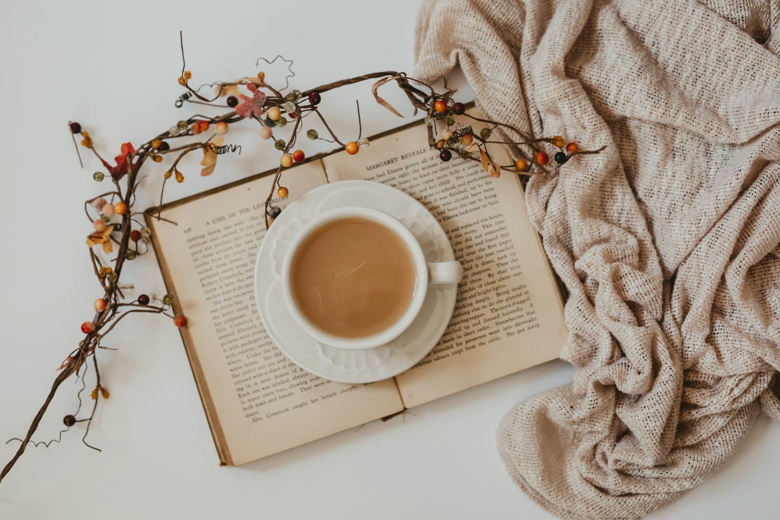 A white mug of coffee resting on an open book