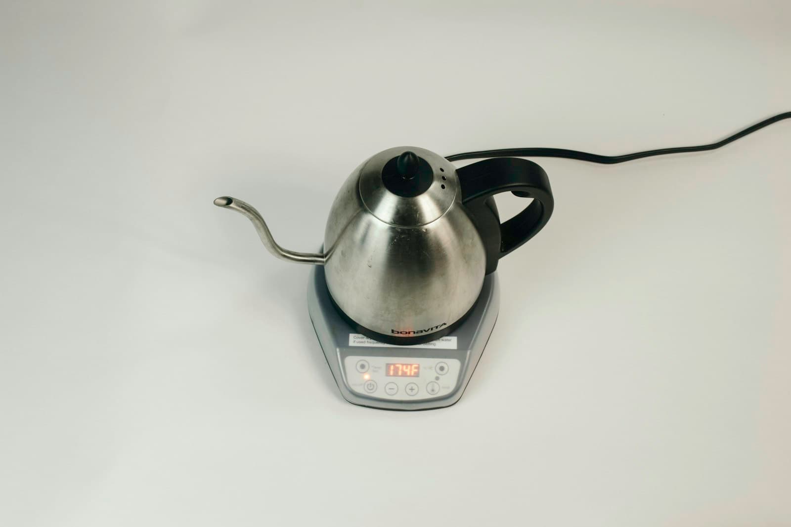 A grey stainless steel electric gooseneck kettle on its base