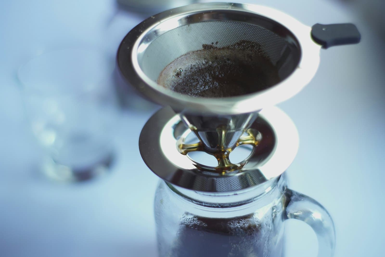 A polished stainless steel cone coffee filter on a table
