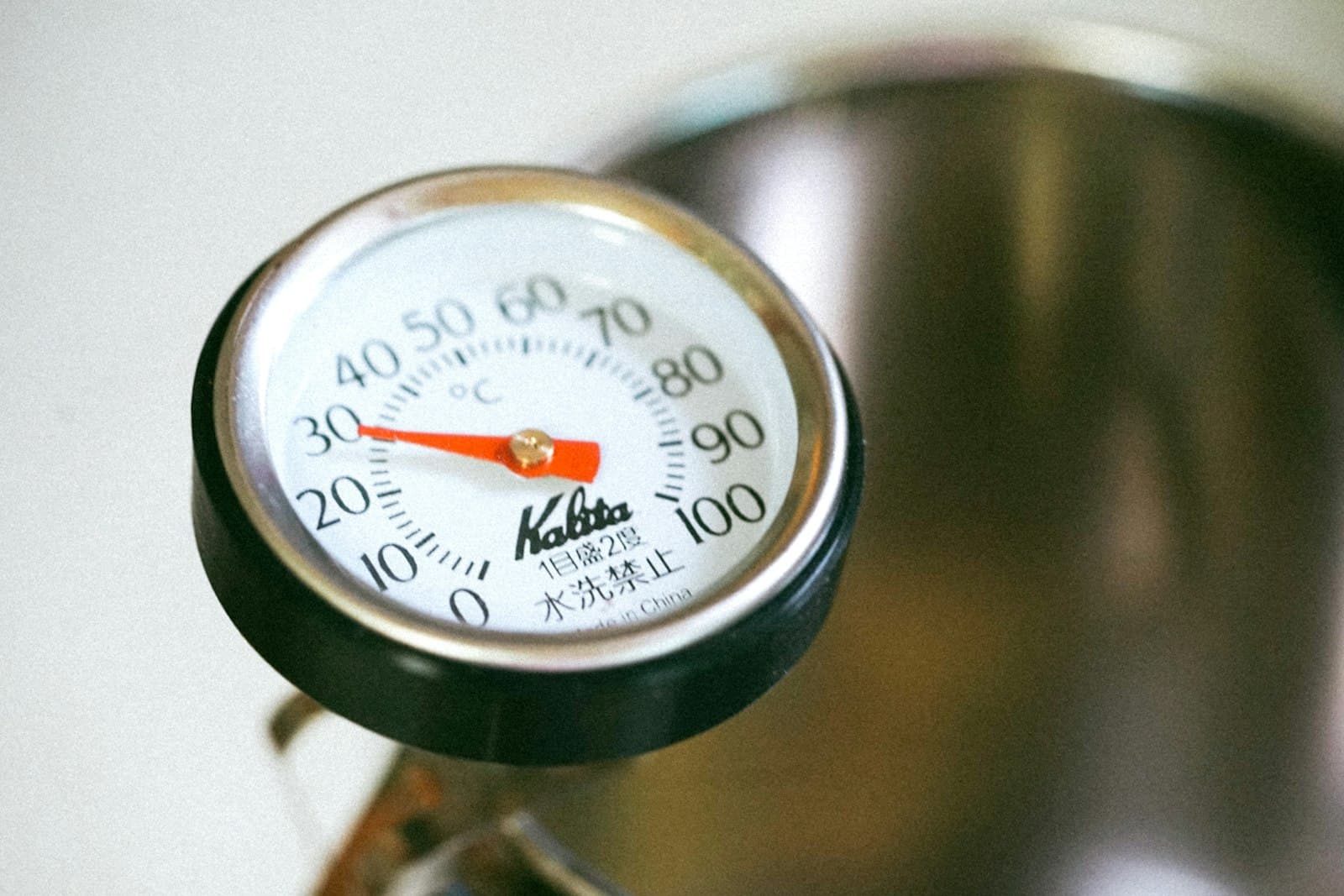 A brewing thermometer gauge clipped to a coffee kettle